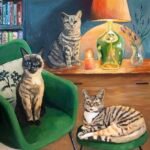 a painting of a siamese cat on a green velvet chair, a ginger tabby on a green velvet stool and a grey tabby sitting on a dresser with a warm lamp. there is a bookcase, a candle and a vase of lavender